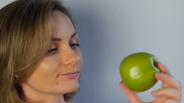 Gezicht portret van een jonge mooie vrouw met grote groene appels in haar handen, bedachtzaam lachend. Het concept van veganistisch en dieet, vers fruit in de handen van een jong meisje, gezond voedsel — Stockvideo