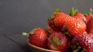 Büyük kırmızı olgun çilek ve yeşil yapraklar bambu bir eko plaka üzerinde sade bir arka plan üzerinde
