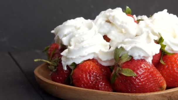 Juicy ripe big red strawberries on an eco bamboo plate on top with whipped cream — Stock Video