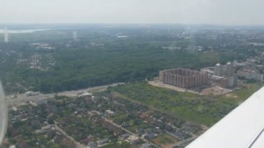 Küçük bir yolcu uçağının penceresinden beyaz bir kanada bakan manzara. Metropolis 'in en üst manzarası. Küçük evler ve arabalar.