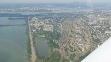 Küçük bir yolcu uçağının penceresinden beyaz bir kanada bakan manzara. Metropolün en üst manzarası, bankalarında evler inşa edilen büyük yeşil bir nehirdir. Küçük arabalar.