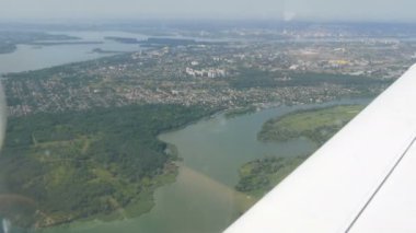 Küçük bir yolcu uçağının penceresinden beyaz bir kanada bakan manzara. Metropolün en üst manzarası, bankalarında evler inşa edilen büyük yeşil bir nehirdir. Küçük arabalar.