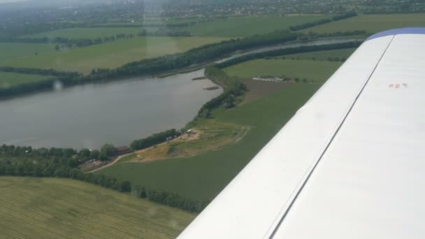 La vue depuis la fenêtre du hublot d'un petit avion de passagers contre une aile blanche. Vue de dessus de la nature, de la rivière et des champs verts sur fond d'aile blanche