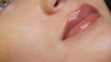 Dudak makyajı ve mikropatenli kaş dövmesi olan genç ve güzel bir kadın ameliyattan sonra güzellik salonunda yatıyor. Yakın plan kız yüzü.