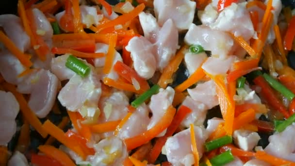 Asiatisk mat. Grönsaker steks i en kastrull med bitar av kyckling. Paprika, morötter, lök, vitlök, gröna skida närbild — Stockvideo