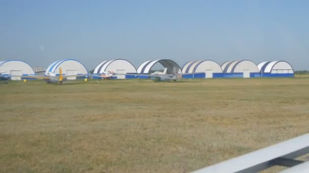 Dnipro, Ukraina - 05 juli 2020: Ett litet passagerarplan landar på flygplatsen. En rad hangarer, mittemot små parkerade flygplan — Stockvideo