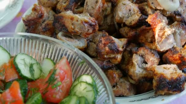 Salade végétarienne fraîche de tomates et de légumes concombres dans un grand saladier à côté de morceaux de viande de porc grillés — Video