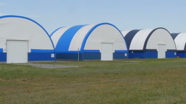 Buitenaanzicht van een reeks hangars voor kleine vliegtuigen op een vliegveld buiten de stad — Stockvideo