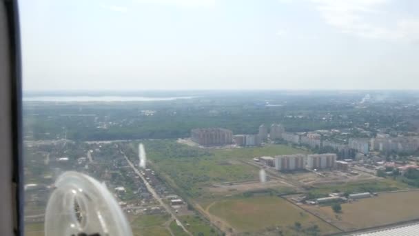 Widok z okna otworu małego samolotu pasażerskiego na białe skrzydło. Widok z góry na metropolię. Małe domy i samochody — Wideo stockowe