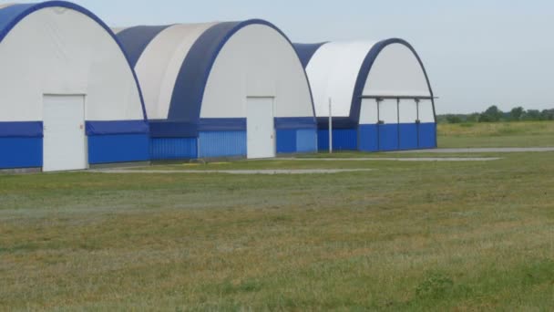 Buitenaanzicht van een reeks hangars voor kleine vliegtuigen op een vliegveld buiten de stad — Stockvideo