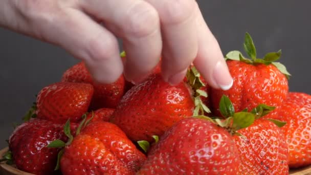 Kadın eli, bambu bir eko tabaktaki yeşil yapraklı sulu kırmızı çilekleri alır. — Stok video