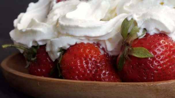 Juicy ripe big red strawberries on an eco bamboo plate on top with whipped cream close up view — Stock Video