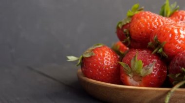 Büyük kırmızı olgun çilek ve yeşil yapraklar bambu bir eko plaka üzerinde sade bir arka plan üzerinde