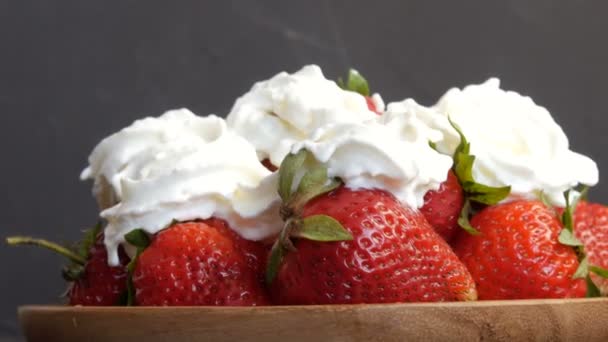 Grandes fraises rouges mûres juteuses sur une assiette en bambou éco sur le dessus avec crème fouettée — Video