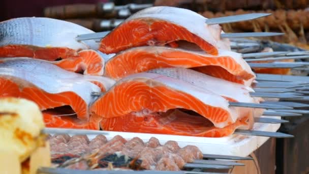 Лосось. Стейк із сирої форелі. Величезні шматки м'яса червоної риби на шампурі готуються для гриля. Відкритий пікнік або вулична їжа. Концепція здорового харчування — стокове відео