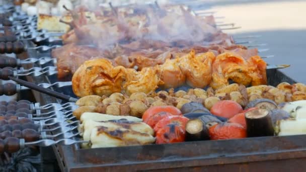 Dlouhá řada zeleniny a kousků masa BBQ na špejlích, připravených k grilování, kouří z grilu. Festival pouličních jídel