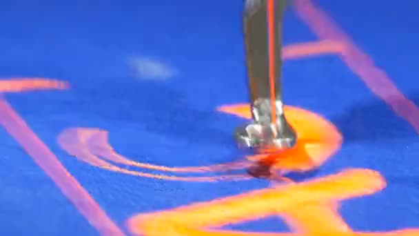 Specjalna igła z maszyny do szycia haftowania pomarańczowe litery na niebieskiej tkaninie w sklepie krawieckim lub warsztacie szycia widok z bliska — Wideo stockowe