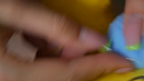 The female hands of a seamstress with a manicure sew on a blue piece of a yellow toy. Sewing workshop, toy factory — Stock Video