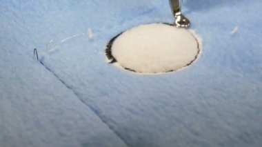 Nakış işlemek için kullanılan dikiş makinesinin iğnesi mavi ve sarı bir kumaş parçasına bir süs yapar. İşyerinde nakış işlemek için özel dikiş makinesi. Programlanabilir dikiş makinesi