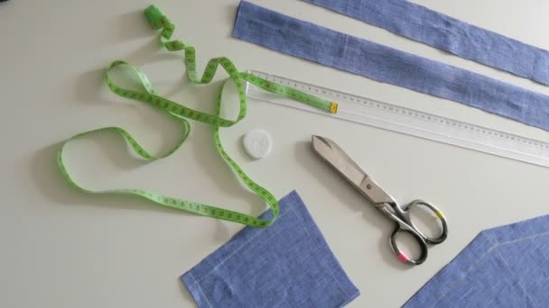 Kit da cucire, forbici da cucire, stracci di tessuto blu, centimetri su sfondo bianco. Laboratorio di cucito, flusso di lavoro della fabbrica del giocattolo — Video Stock