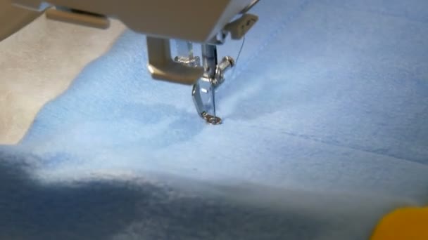 La aguja de la máquina de coser para bordar hace un adorno en un pedazo de tela azul y amarilla. Máquina de coser especial para bordar en el trabajo. Máquina de coser programable — Vídeo de stock