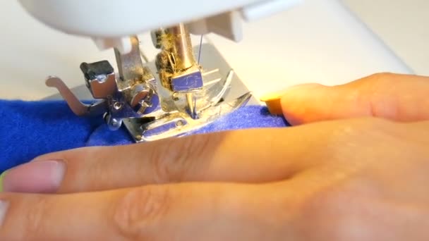 Joven costura de costura de la mano de la mujer cose en una máquina de coser. La aguja y el pie de una máquina de coser con hilo hacen puntadas en la tela — Vídeos de Stock