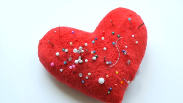 Coussin en forme de coeur rouge doux dans lequel de nombreuses épingles et aiguilles pour la broderie et la couture sont collées dans un atelier de couture ou un atelier — Video