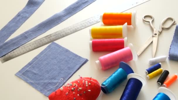 Kit de costura, tijeras de coser, bobinas con hilo, almohadilla con agujas, centímetro sobre un fondo de mesa blanco. Taller de costura, fábrica de juguetes — Vídeos de Stock