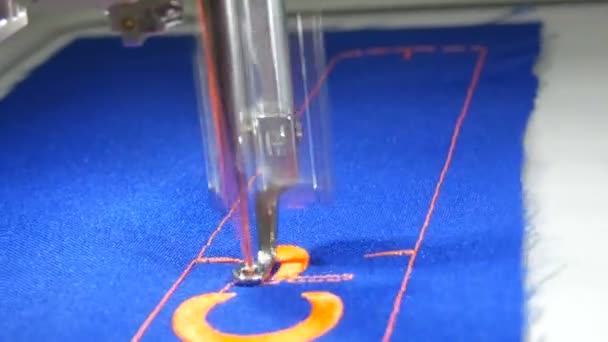 Специальная игла из швейной машинки вышитые оранжевые буквы на голубой ткани в портной мастерской или швейной мастерской закрыть вид — стоковое видео