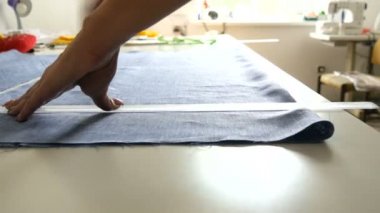 Kadın terzilerin elleri özel tebeşir ve cetvel kullanarak desen üzerinde izler bırakır. Dikiş atölyesi, oyuncak fabrikası iş akışı