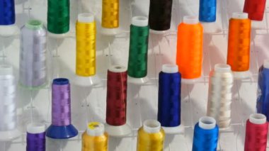 Dikiş makinesi için bir sıra çok renkli iplik ve dikiş atölyesi ya da atölyesinde kilit. Endüstriyel dikiş makinesinde farklı renk ipliklerinin makaralarını ayarlar.