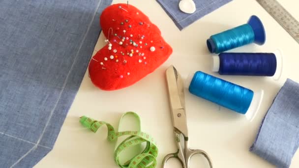 Kit de costura, tijeras de coser, bobinas con hilo, almohadilla con agujas, centímetro sobre un fondo de mesa blanco. Taller de costura, fábrica de juguetes — Vídeos de Stock