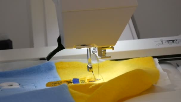 Jehla šicího stroje pro vyšívání vytváří ozdobu na kusu modré a žluté textilie. Speciální šicí stroj pro vyšívání při práci. Programovatelný šicí stroj — Stock video