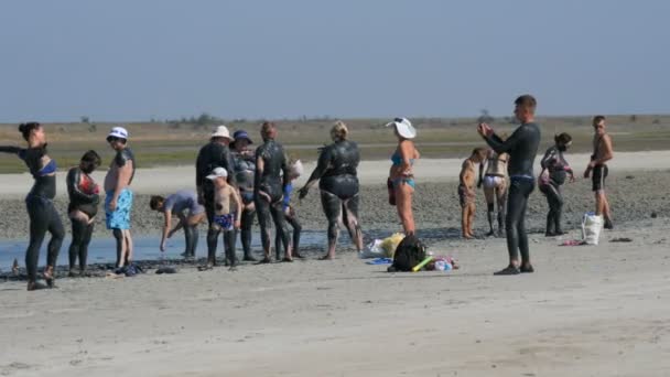 Schastlivtsevo, Ucrania - 3 de agosto de 2020: Multitud de personas aplicadas a la piel curando lodo médico negro en el lago de agua salada. Suciedad negra salada para personas con problemas de salud y piel. Relájese en — Vídeos de Stock