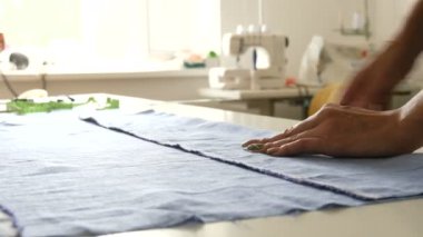 Kadın terzilerin elleri özel tebeşir ve cetvel kullanarak desen üzerinde izler bırakır. Dikiş atölyesi, oyuncak fabrikası iş akışı