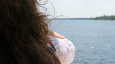 Genç bir kızın güzel, uzun siyah saçları yaz aylarındaki bir tekne gezisinin arka planında rüzgarda sallanıyor, mavi berrak su parıldıyor ve güneş ışığını yansıtıyor. Rahatla konsept, dinlen