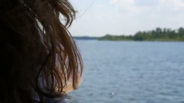 Genç bir kızın güzel, uzun siyah saçları yaz aylarındaki bir tekne gezisinin arka planında rüzgarda sallanıyor, mavi berrak su parıldıyor ve güneş ışığını yansıtıyor. Rahatla konsept, dinlen