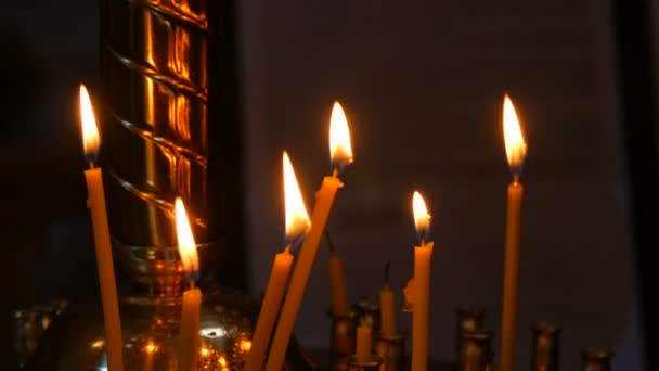 Dlouhé tenké voskové svíčky hoří plamenem v pravoslavném kostele, pamětní rituály pro křesťany — Stock video
