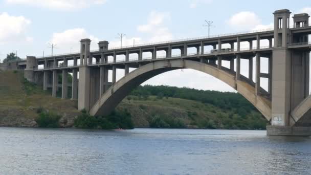 Zaporoże, Ukraina - 19 czerwca 2020: Turystyczny statek wycieczkowy pływa pod dużym starym betonowym mostem w pobliżu widoku. — Wideo stockowe