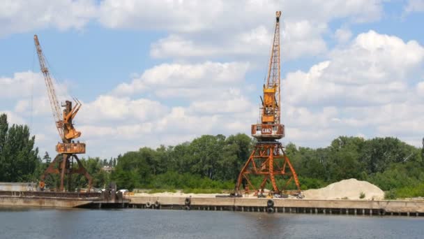 Zaporozhye, Ukrayna - 19 Haziran 2020: Nehrin kıyısında ya da gölette bulunan bir mavnanın arka planında duran bir dizi inşaat ya da kargo vinci. — Stok video