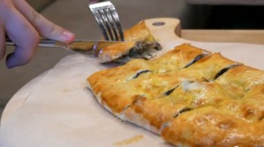 Gürcü restoranında lezzetli bir Gürcü etli turtası, çatal ve bıçakla parçalara ayrılmış. Ulusal otantik mutfak şık yemeklerle servis edilir.