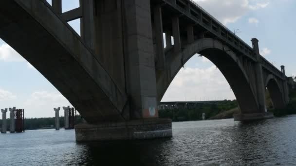 Saporizhzhia, Ukraine - 19. Juni 2020: Touristisches Ausflugsboot segelt unter einer großen alten Betonbrücke in Sichtweite. — Stockvideo