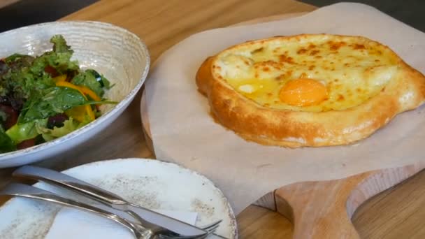 Délicieux khachapuri géorgien Adjarian dans le restaurant géorgien, cuisine nationale authentique. Salade végétarienne de légumes verts et de tomates, paprika, concombres de laitue, servie sur un plat élégant — Video