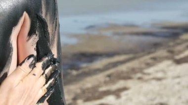 Anne eli, tuzlu su gölünde oğlunun koluna çamur bulaştırıyor. Tuzlu siyah çamur, sağlık ve deri sorunları olan insanlar için iyidir. Kaplıca merkezinde rahatla. Deri dökülmesi güzellik tedavisini temizler