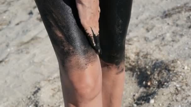 Leczenie czarnego błota medycznego odnosi się do nogi i kolana kobiety nad jeziorem słonej wody. Słony czarny brud dla osób z problemami zdrowotnymi i skórnymi. Zrelaksuj się w spa. Złuszczanie peeling uroda leczenie — Wideo stockowe