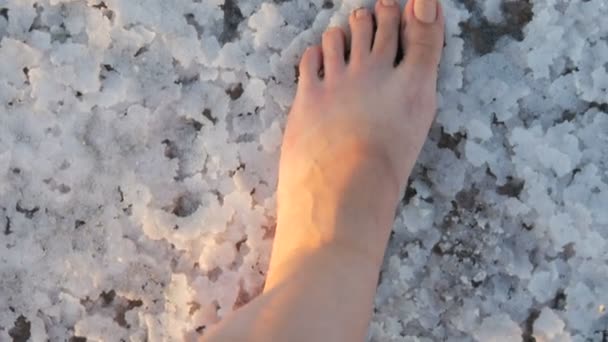 Ukrayna 'nın Kherson bölgesindeki tuz gölü çıkarma fabrikası Sivash' ta beyaz tuzlu kabuk üzerinde yürüyen bir kadının ayakları. — Stok video