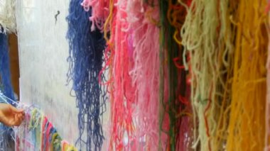 Çok sayıda farklı yün iplikler. El yapımı halı nakışı. Kadınların elleri çok renkli iplikler kullanarak bir desen oluşturur. Nakışlar için çekiç, iplikler için dolgu.