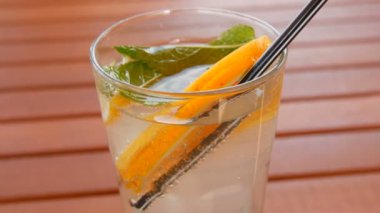 Limonata soğanları bir bardakta portakal, limon, nane dilimleri, ahşap bir masada meyve suyu için kamış, yaz serinletici bir içecek.