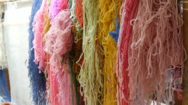 Çok sayıda farklı yün iplikler. El yapımı halı nakışı. Kadınların elleri çok renkli iplikler kullanarak bir desen oluşturur. Nakışlar için çekiç, iplikler için dolgu.