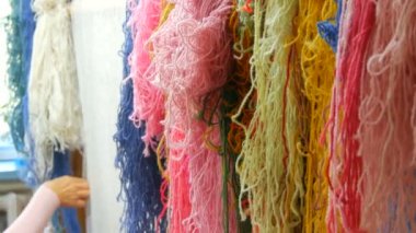 Çok sayıda farklı yün iplikler. El yapımı halı nakışı. Kadınların elleri çok renkli iplikler kullanarak bir desen oluşturur. Nakışlar için çekiç, iplikler için dolgu.